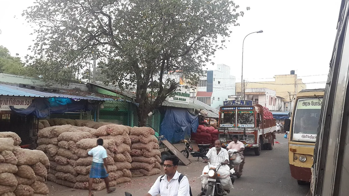 मंडी में गाड़ी से प्याज़ की बोरियाँ उतारते मज़दूर